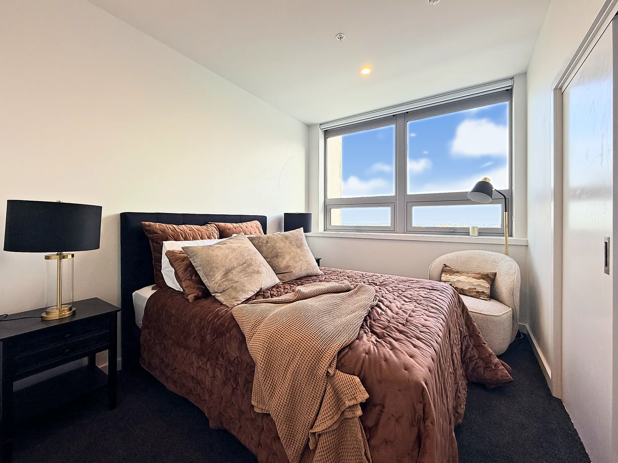 Main bedroom with a wide window in a two bedroom corner display home at Avalon Apartments, Lower Hutt